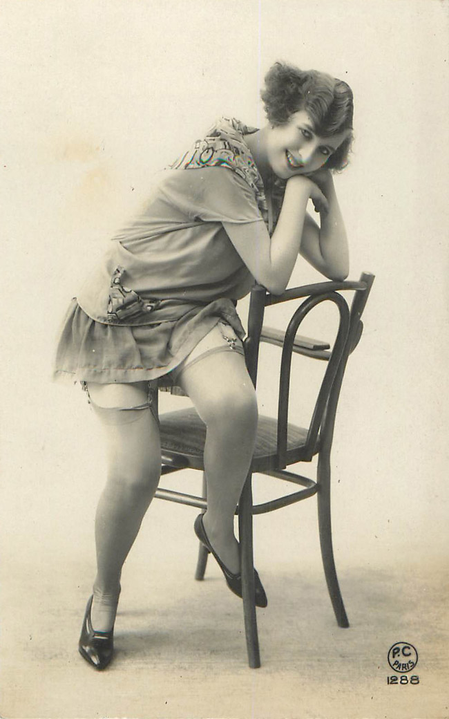 Lady sitting on arm of chair, leaning on the back - French Risqu